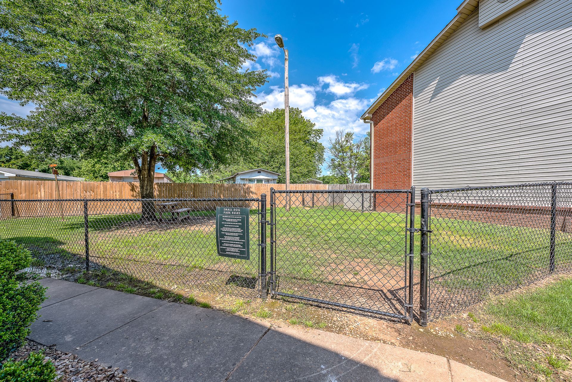 A chain link fence surrounds a grassy yard in front of a house.