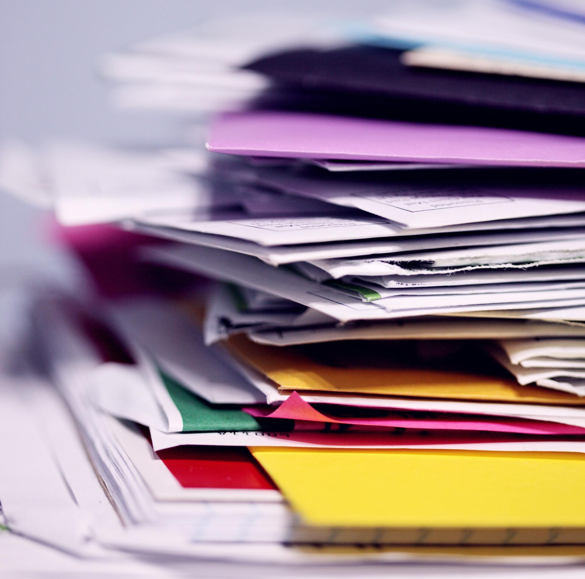 A stack of colorful papers and envelopes on a table