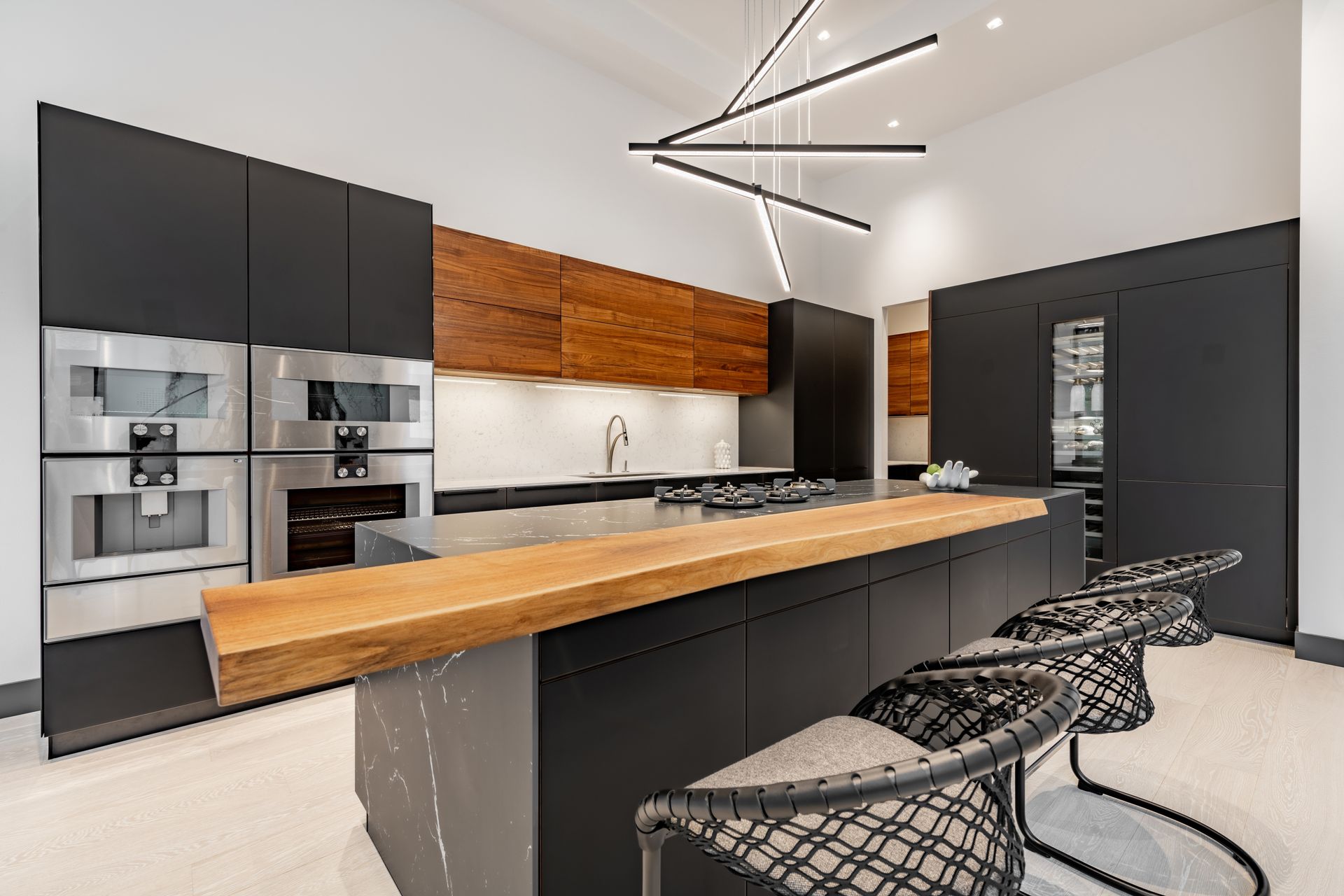 Modern kitchen with black cabinets, wood island, stainless appliances, and wire bar stools.