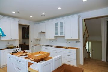 Bright white kitchen with island, wood floors, and open doorway to a stairway area