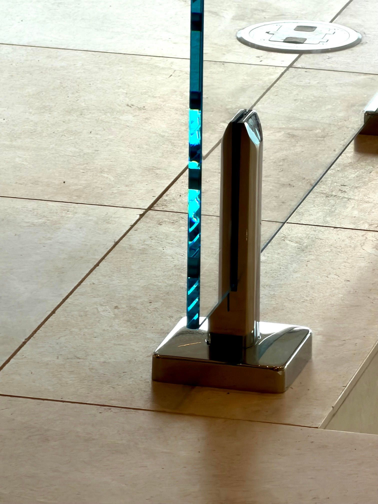 Close-up of a metal floor stanchion with a blue striped post on a tiled floor.