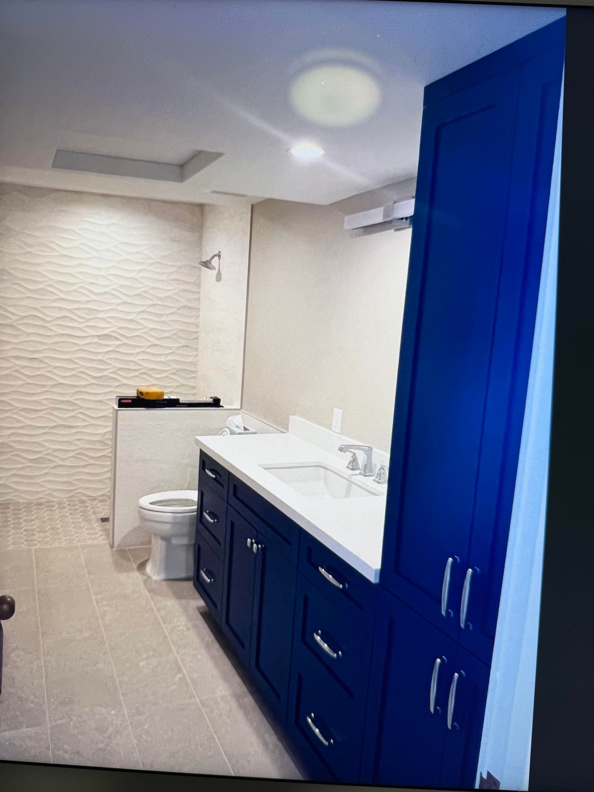 Bathroom interior with blue vanity, white countertop, toilet, and shower curtain.