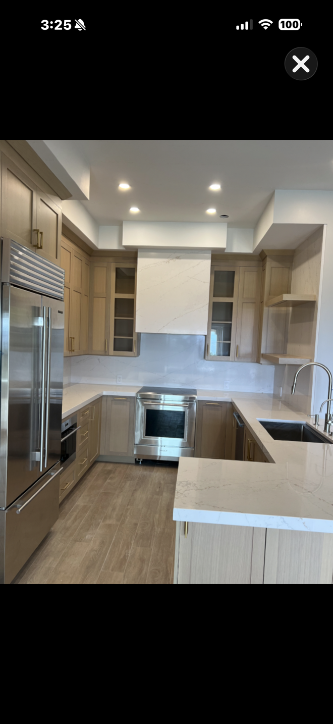 Modern kitchen with light wood cabinets, stainless appliances, white countertops, and an island.