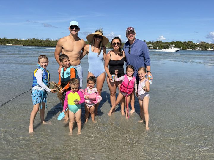 Group of people posing at the beach in shallow water on a sunny day