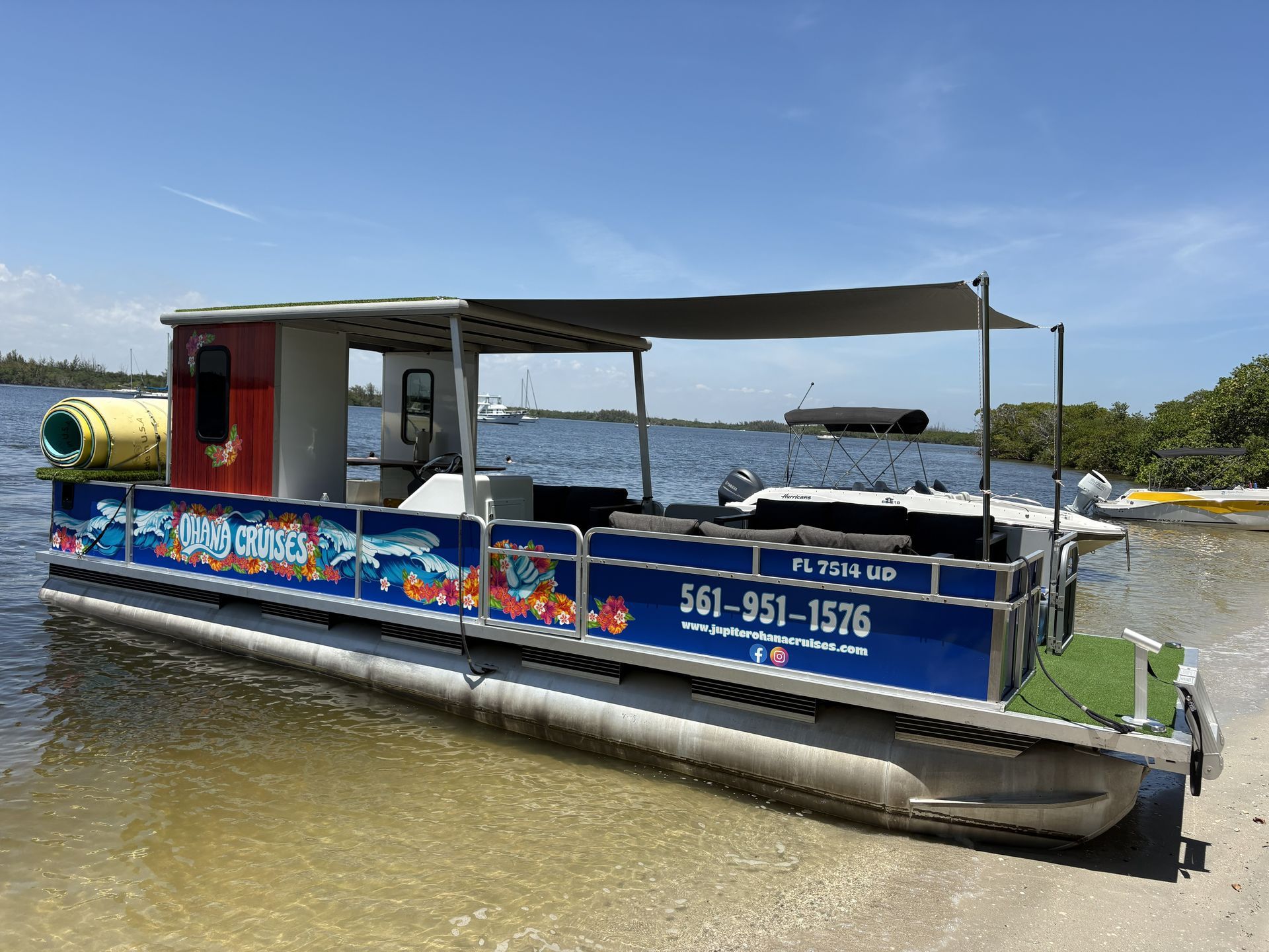 Pontoon boat with colorful side panels on calm water under a clear blue sky