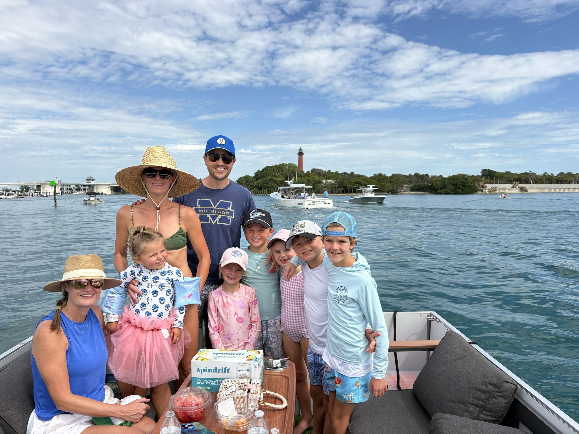 Family posing on a boat deck with a harbor and lighthouse in the background