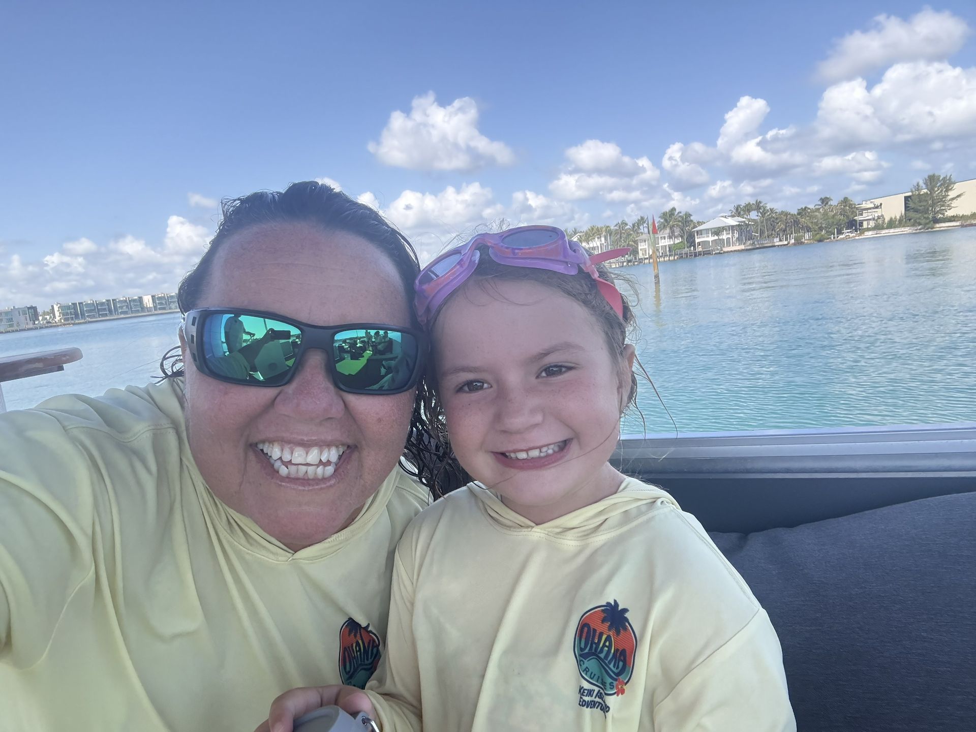 Two smiling people in yellow hoodies taking a selfie by the water on a boat