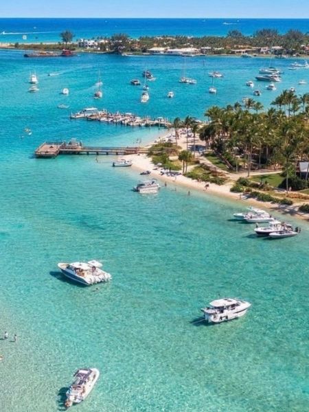 Turquoise lagoon with boats and a sandy tropical shoreline lined with palm trees