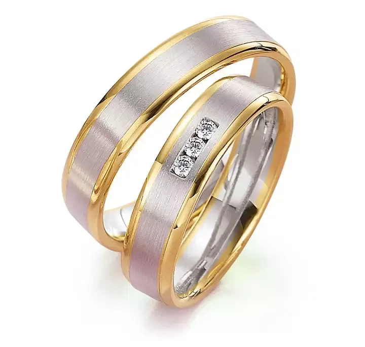 Tweekleurige trouwringen: gouden randen, zilveren banden en één ring met drie kleine diamanten.