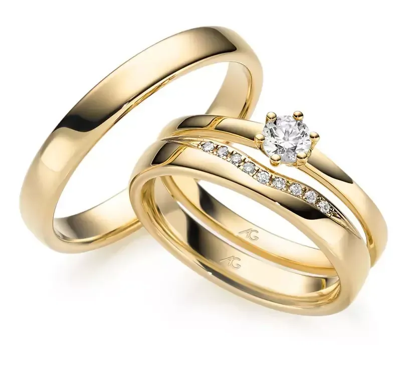 Twee gouden trouwringen, één eenvoudig en één met een diamant en kleinere edelstenen.