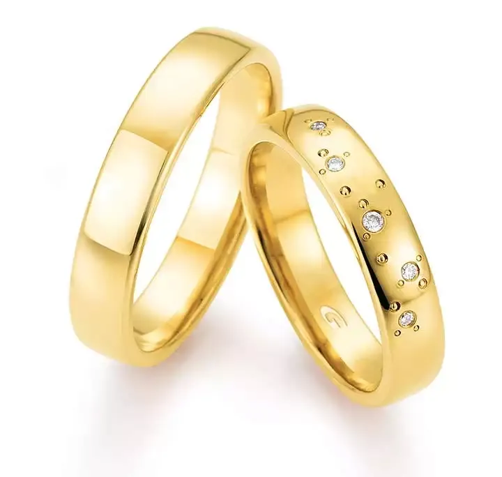 Twee gouden trouwringen, één eenvoudig en de andere bezet met kleine diamantjes.
