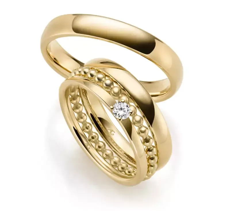 Twee gouden trouwringen, één eenvoudig en de andere met een diamant en kralendetail.
