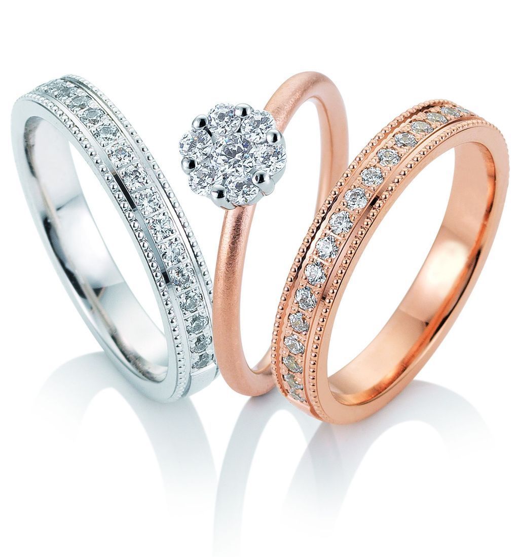 Drie ringen met diamanten: een band van witgoud, een band van roségoud en een ring van roségoud met een diamantencluster.