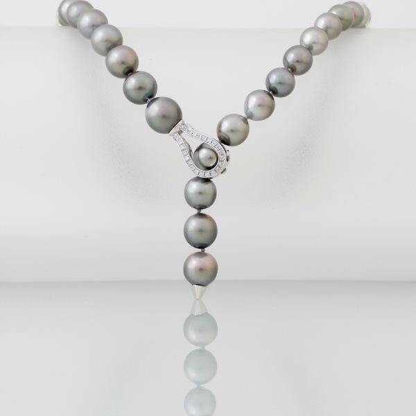 Grijze parelketting met diamanten sluiting, witte achtergrond.