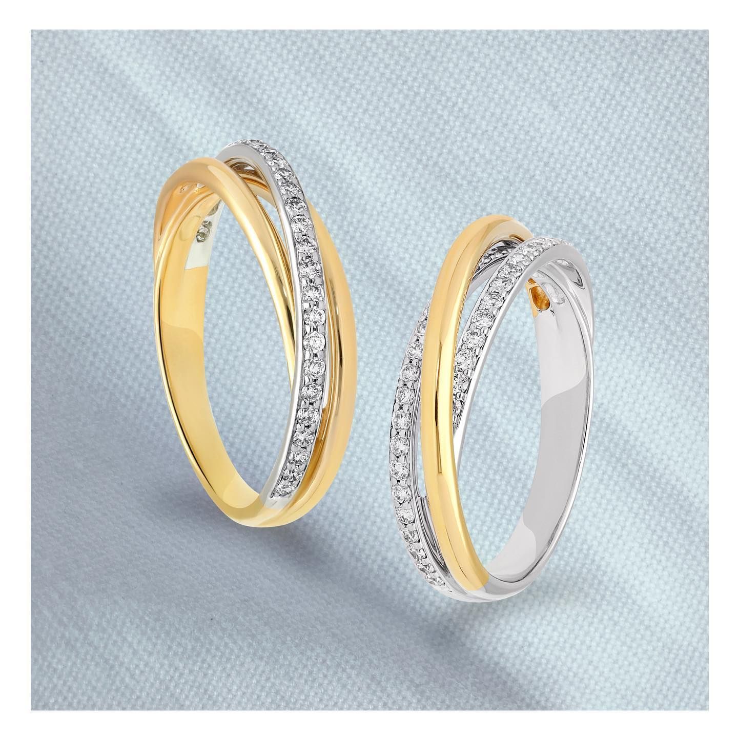 Twee in elkaar grijpende ringen, één van goud en één van zilver, met een rij kleine diamantjes.
