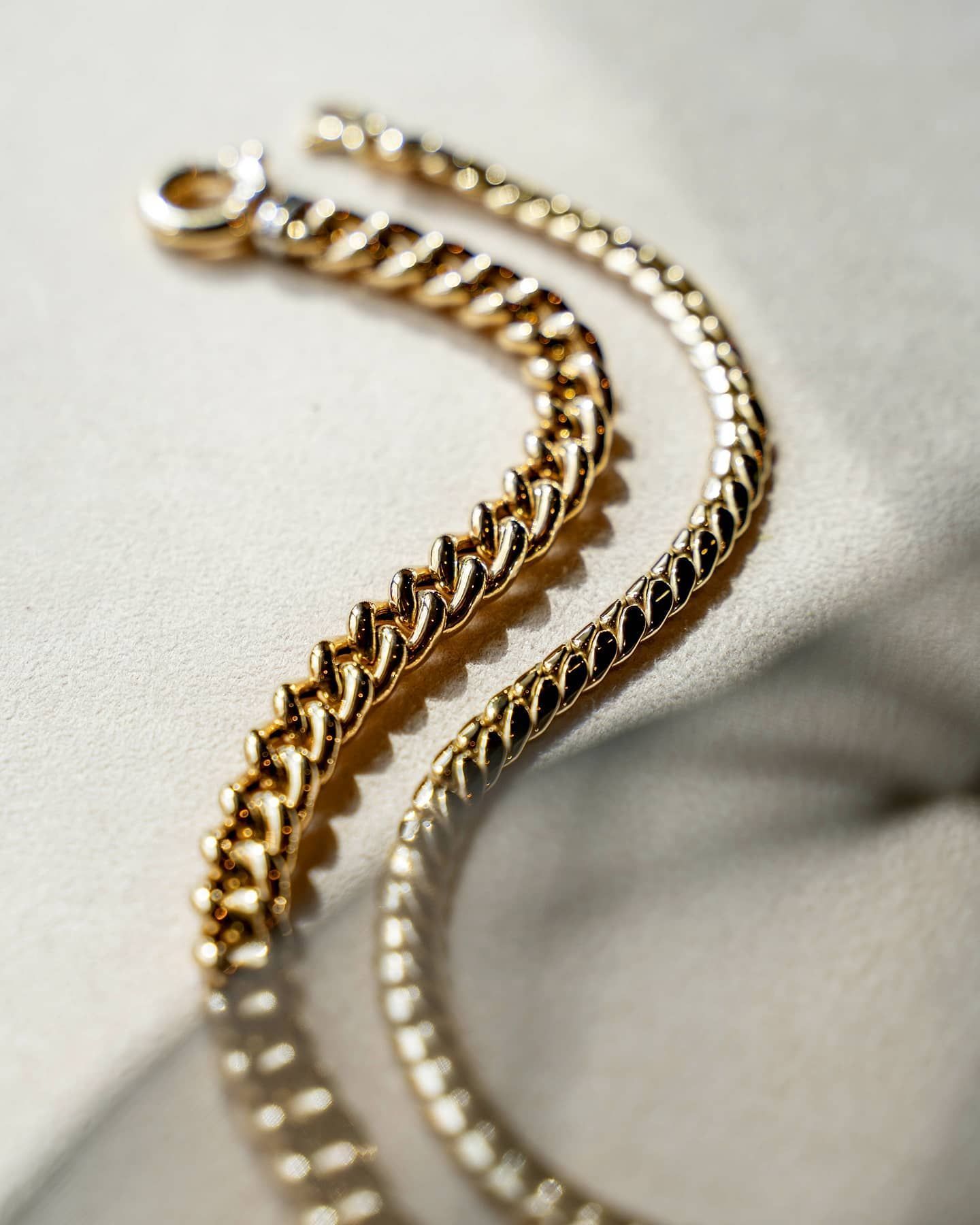 Gouden ketting gedrapeerd op een lichtgekleurd oppervlak; close-up.