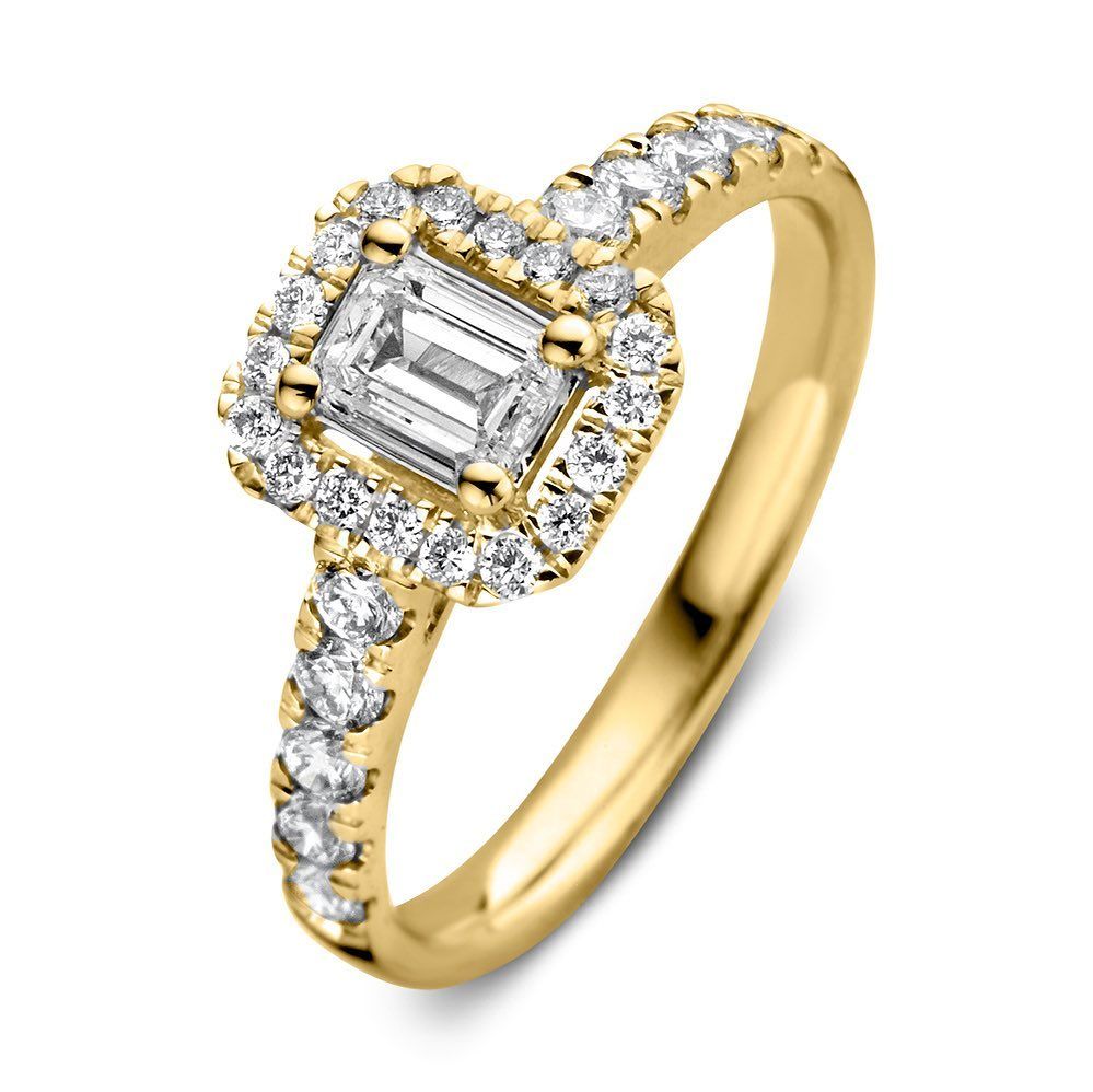 Gouden ring met een smaragdgeslepen diamant in het midden, omringd door een halo van kleinere diamanten, met diamantaccenten op de band.