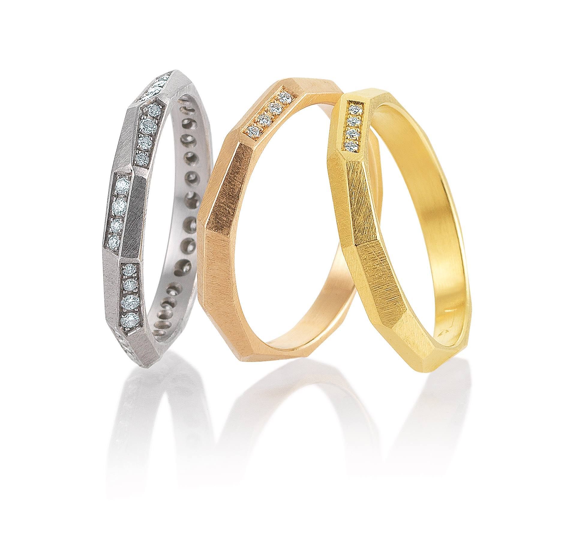 Drie gefacetteerde metalen ringen in zilver, roségoud en geelgoud, waarvan sommige met diamanten accenten.