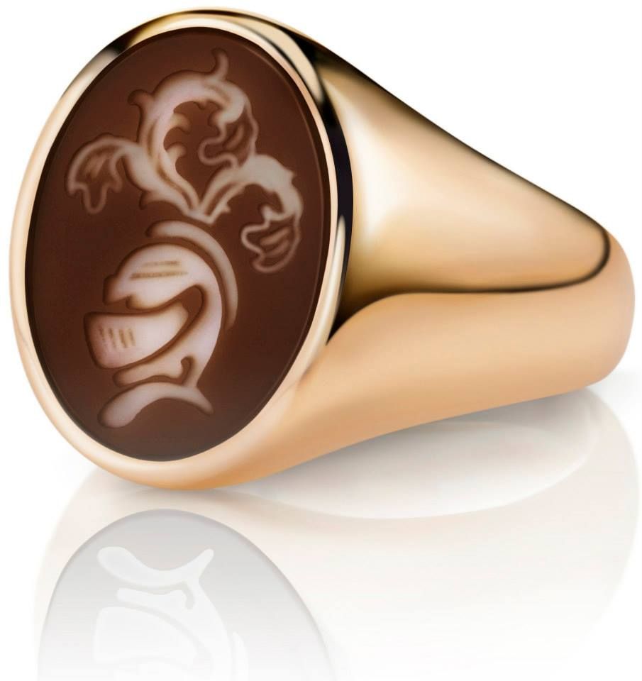Gouden zegelring met een bruine ovale camee met een witte ridderhelm en bloemmotief.