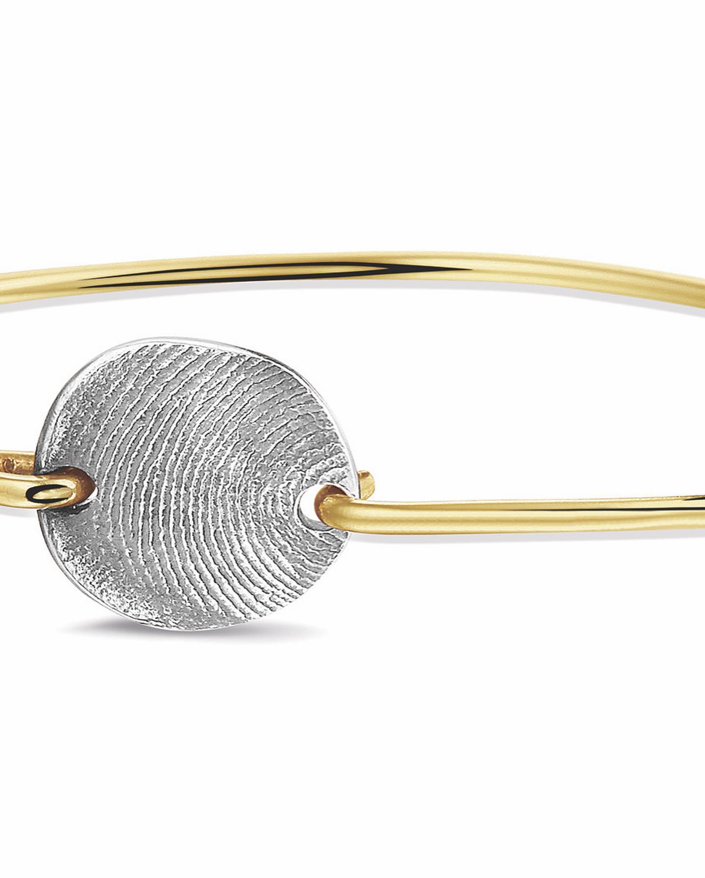 Gouden armband met een zilveren vingerafdrukbedel.