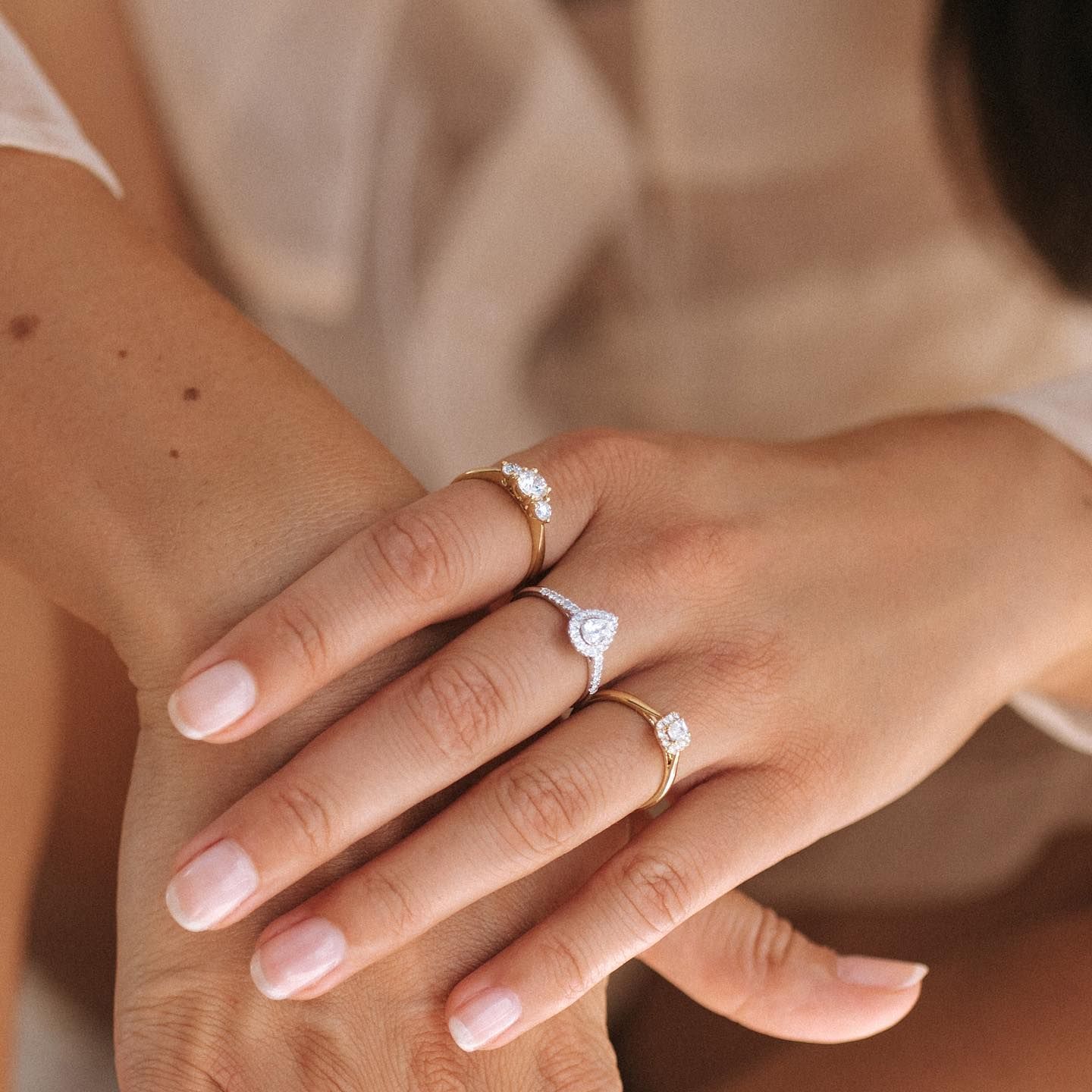 Een vrouwenhand met drie ringen. Op de achtergrond een wit overhemd.