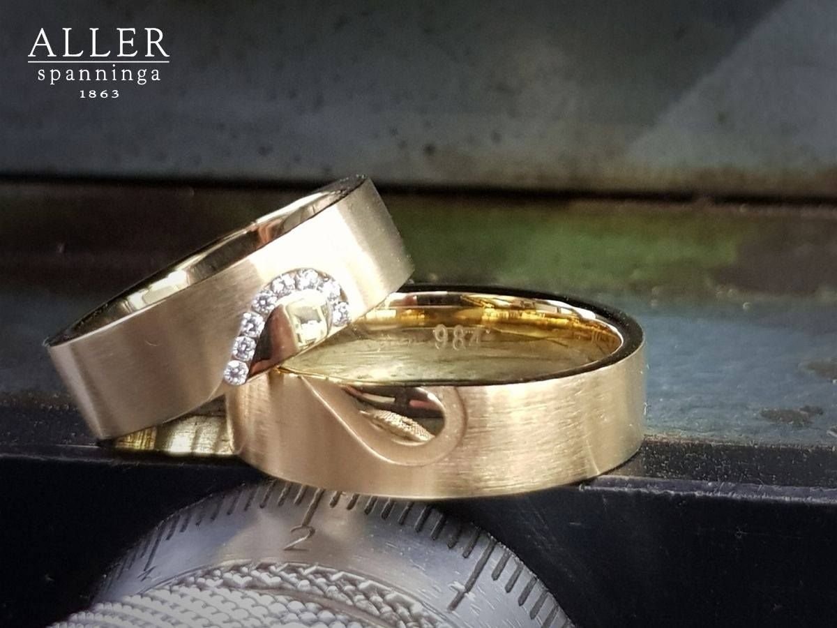 Twee gouden trouwringen, één met diamanten en een gebogen ontwerp, de andere met een uitgesneden hart.