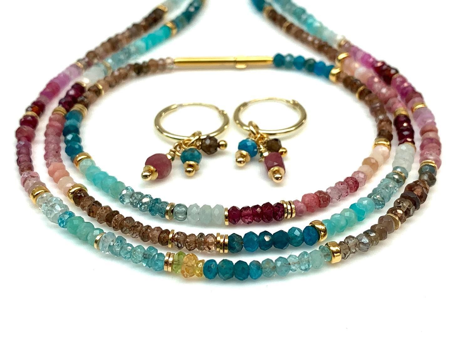 Ketting en oorbellen met kleurrijke edelsteenkralen en gouden accenten.