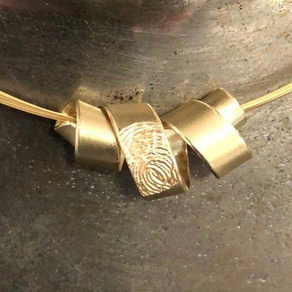 Gouden ketting met drie lintvormige lussen, waarvan er één is voorzien van een vingerafdruk.