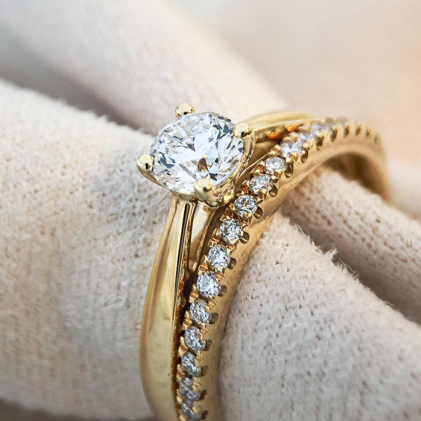 Gouden verlovingsring met diamant en bijpassende band op een witte doek.
