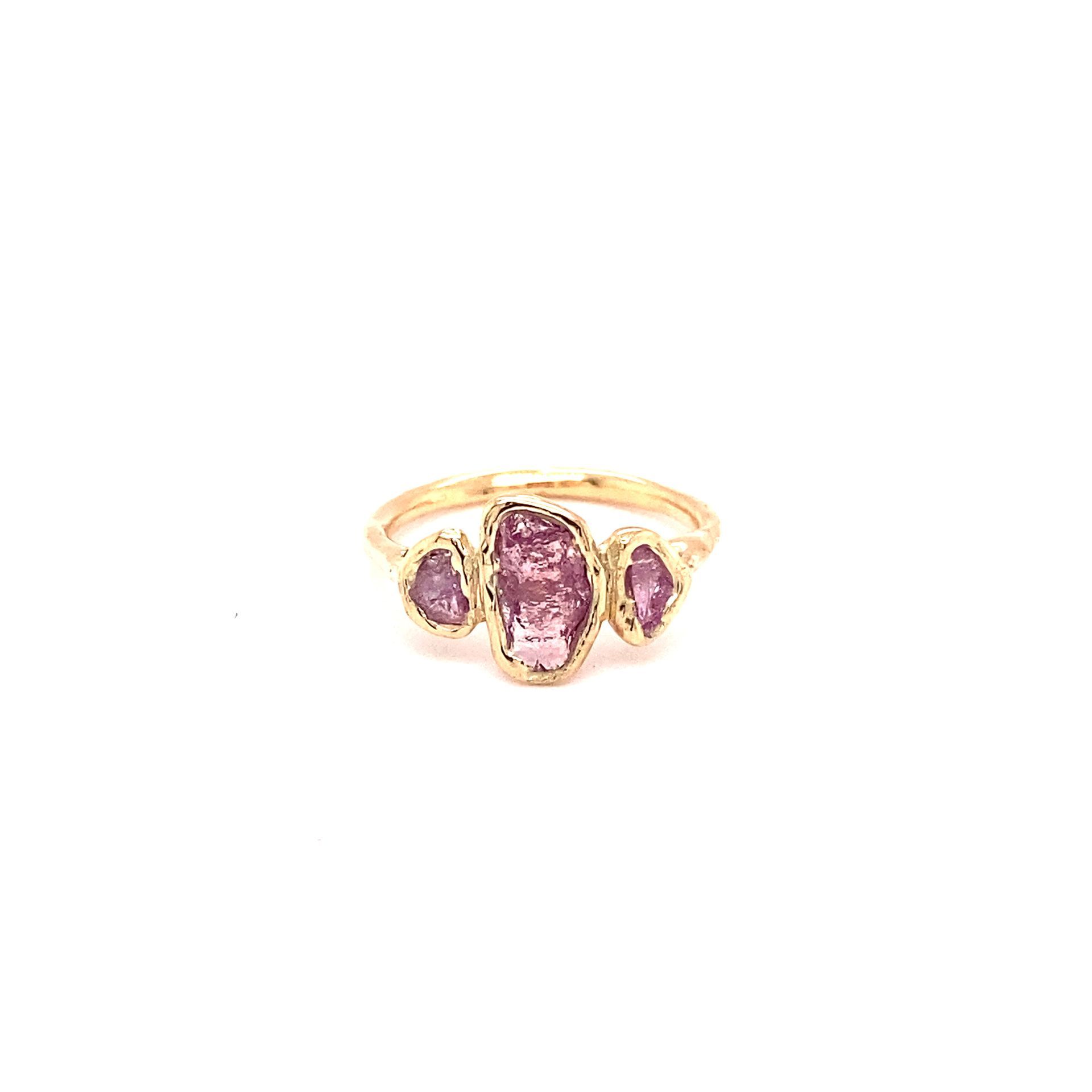 Gouden ring met drie roze edelstenen.