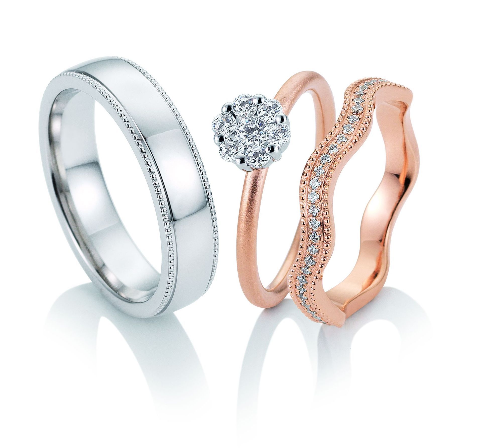 Drie trouwringen: zilveren band, roségouden band met diamant, roségouden golvende band met diamanten.