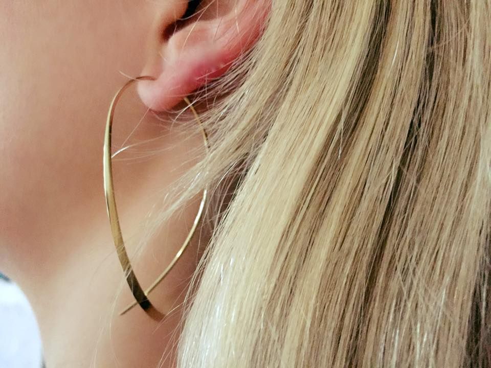 Gouden creolen aan het oor van een persoon, met zichtbaar blond haar.