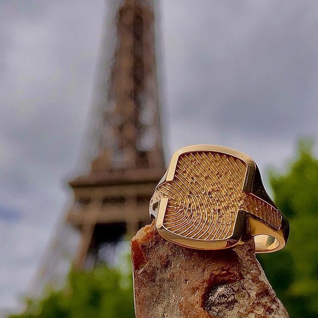 Gouden ring met geëtst ontwerp, met de Eiffeltoren in Parijs als achtergrond.