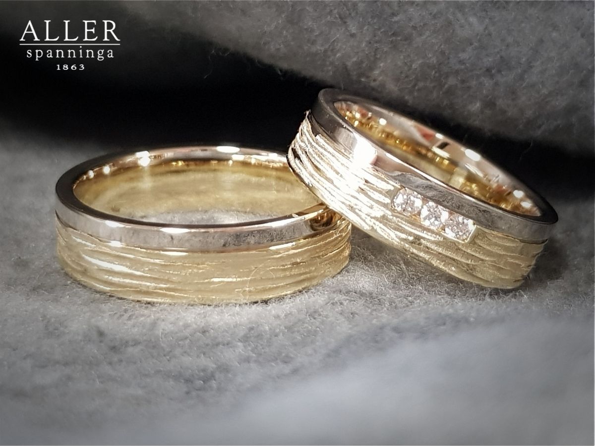 Twee trouwringen met een structuurpatroon; één ring heeft drie kleine diamanten.
