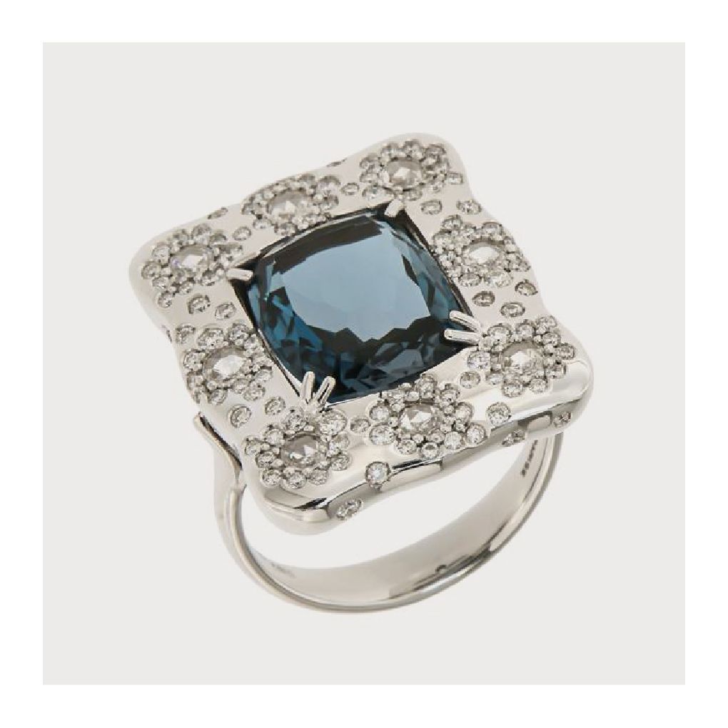 Zilveren ring met een blauwe edelsteen in het midden, omringd door bloemen en diamanten.