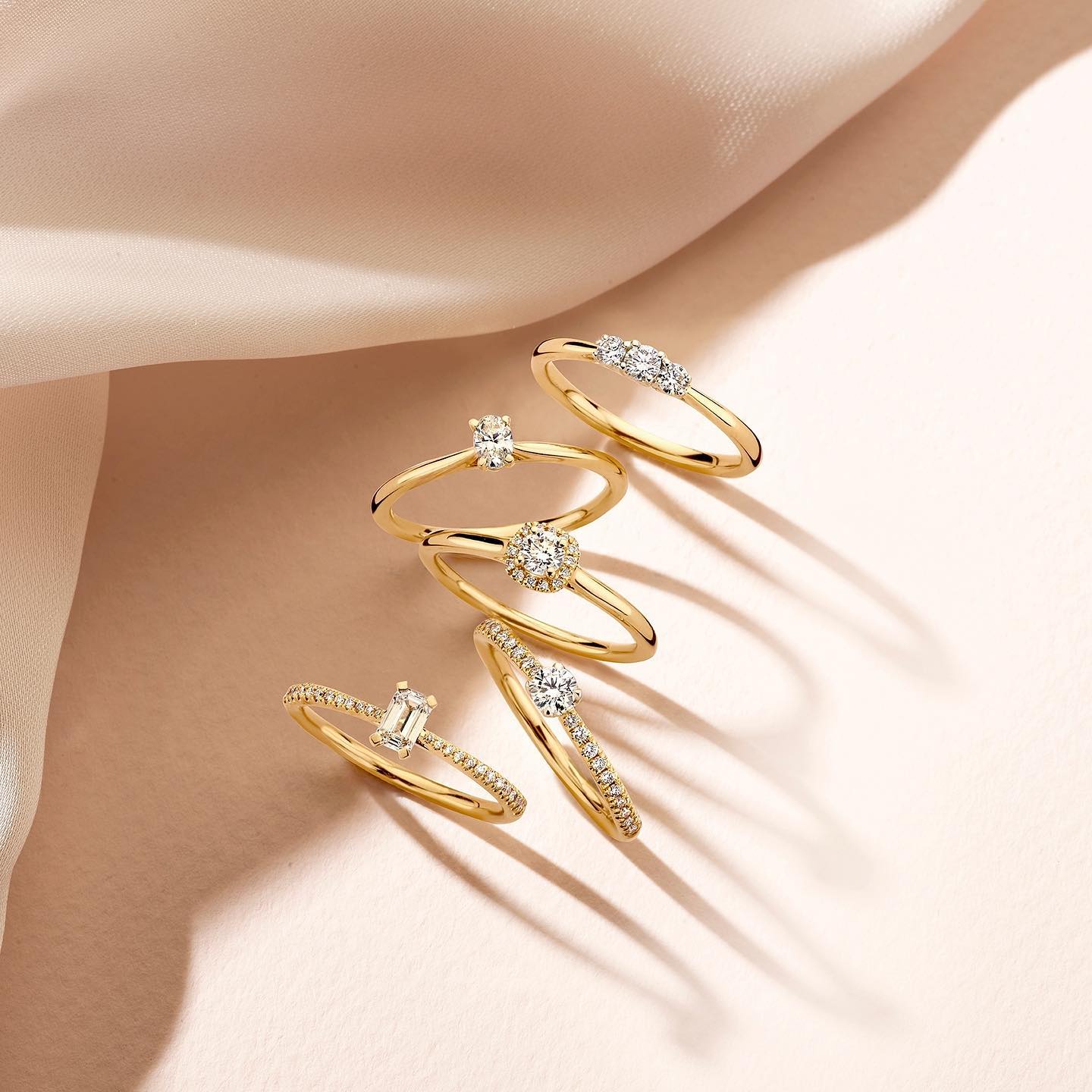 Gouden ringen met diamanten op een roze doek.