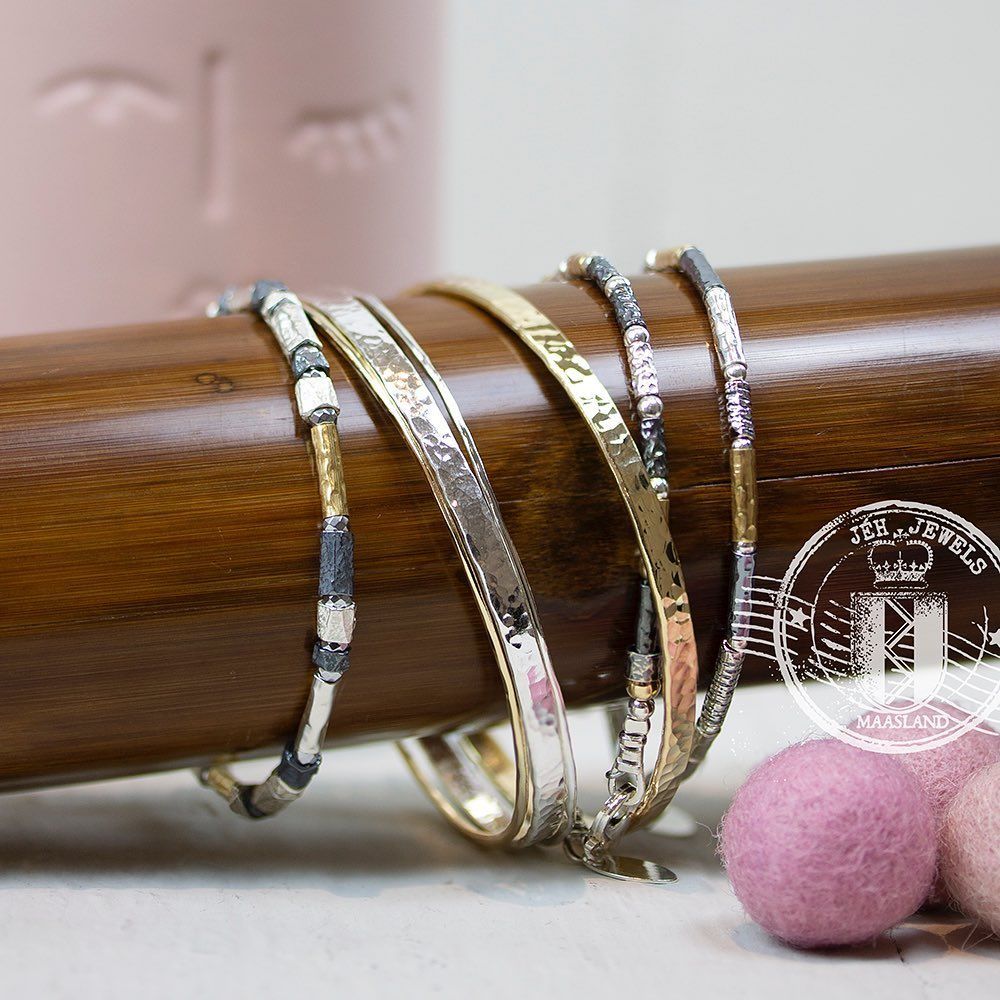 Armbanden aan een houten staaf met roze achtergrond.