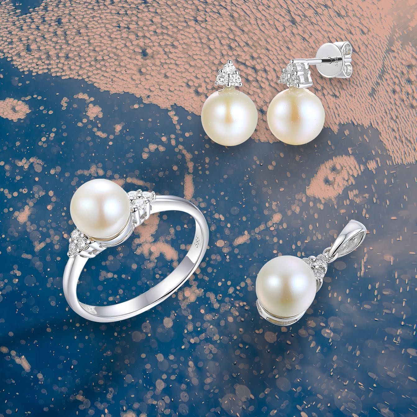Sieradenset met parels: ring, oorbellen en hanger op een blauw en goudkleurig oppervlak.