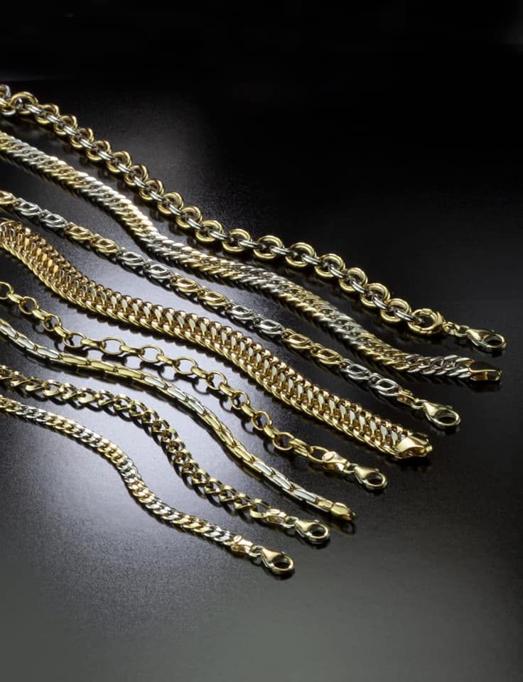 Armbanden van goud en zilver, gerangschikt op een donker oppervlak.