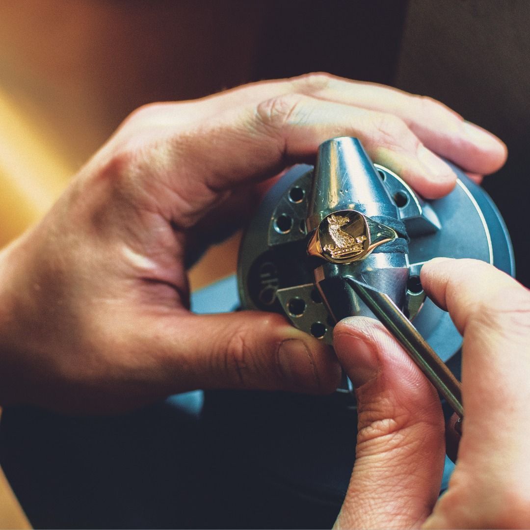 Handen die een ring vasthouden met een pincet, geplaatst in een metalen gereedschap, voor het maken van sieraden.