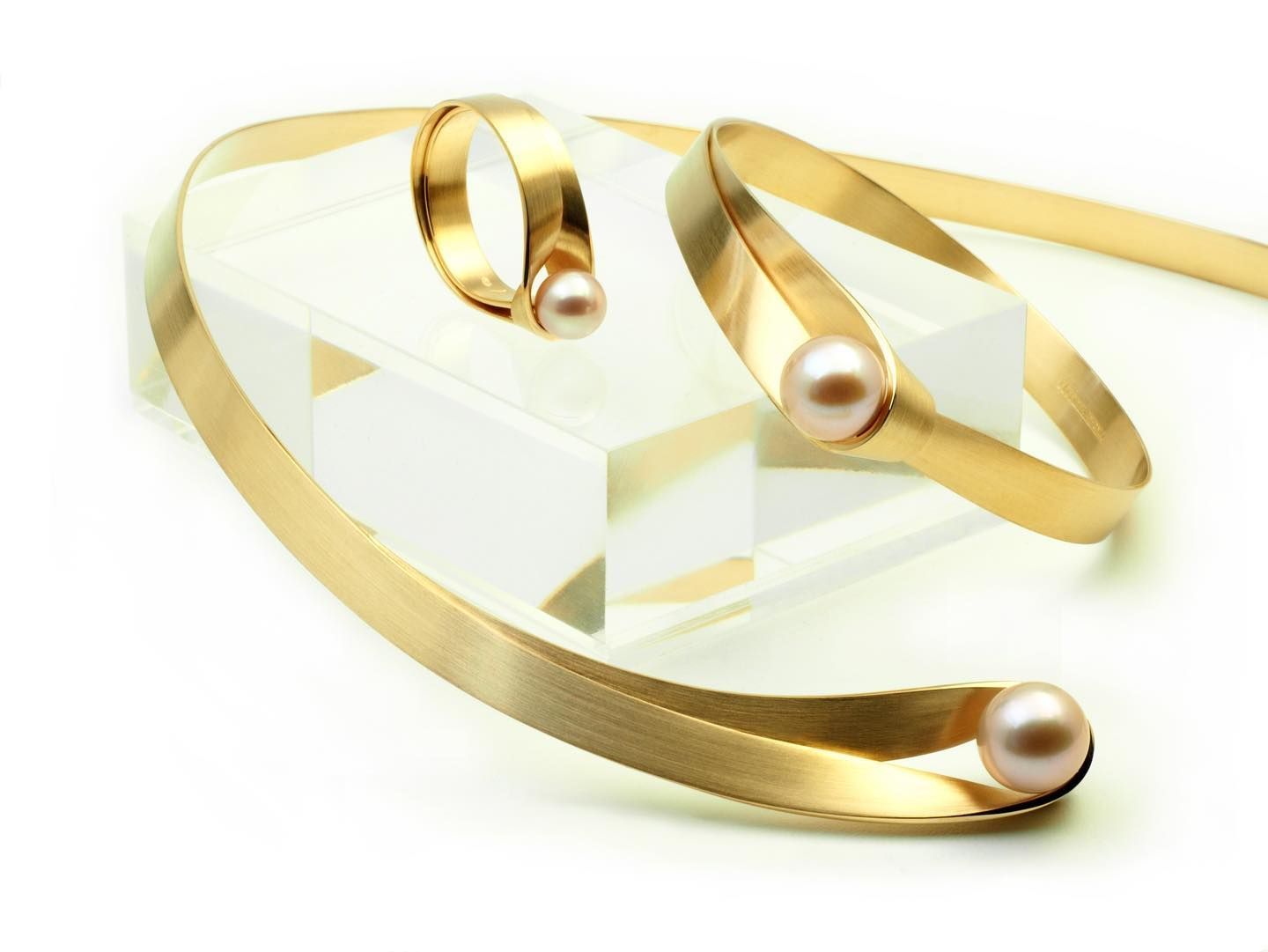 Gouden sieradenset met parels: ring, armband en choker op een wit blok, geïsoleerd.