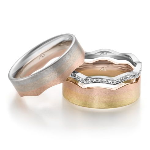 Driekleurige gouden ringen: geborsteld goud, roségoud en zilver. Eén ring heeft diamanten, alle ringen hebben een golvend ontwerp.