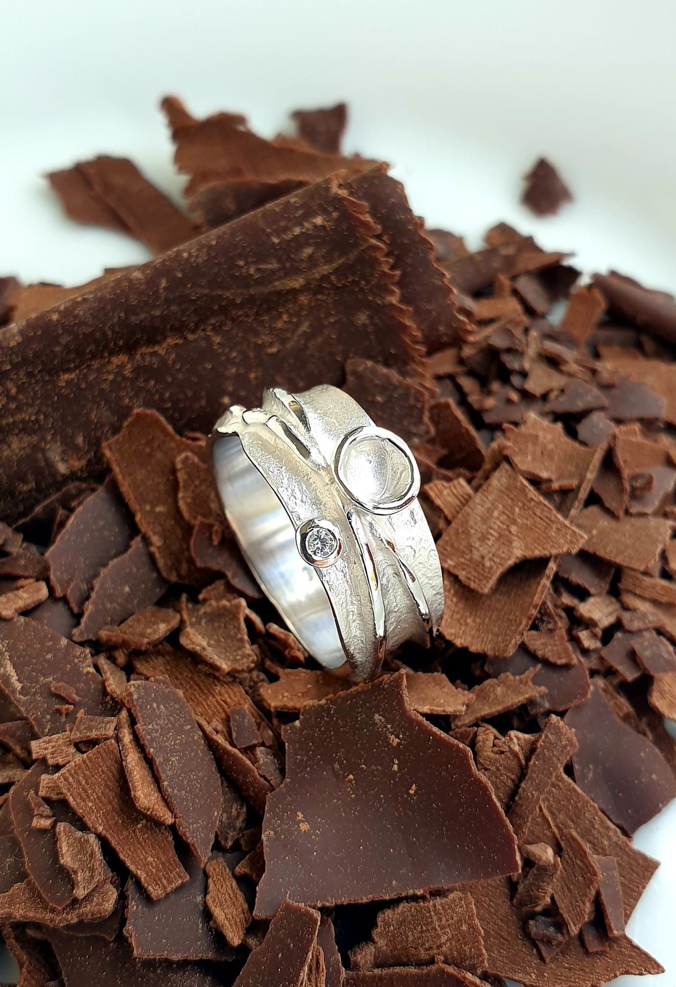 Zilveren ring met twee stenen op donkere chocoladeschaafsel.