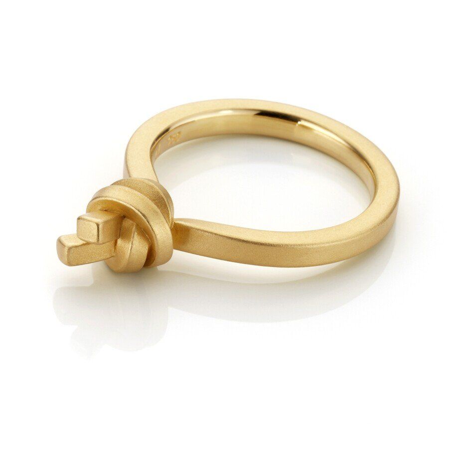 Goudkleurige ring met een knoopmotief op een wit oppervlak.