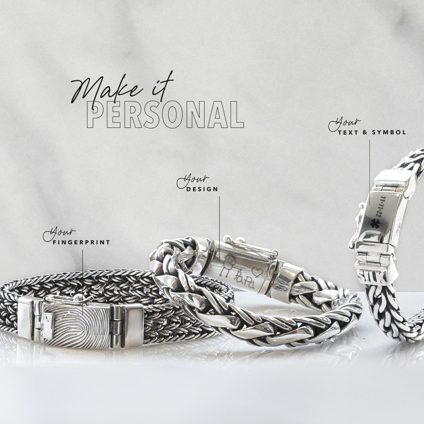 Zilveren armbanden op een marmeren achtergrond met personalisatiemogelijkheden: tekst, symbool, ontwerp of vingerafdruk.