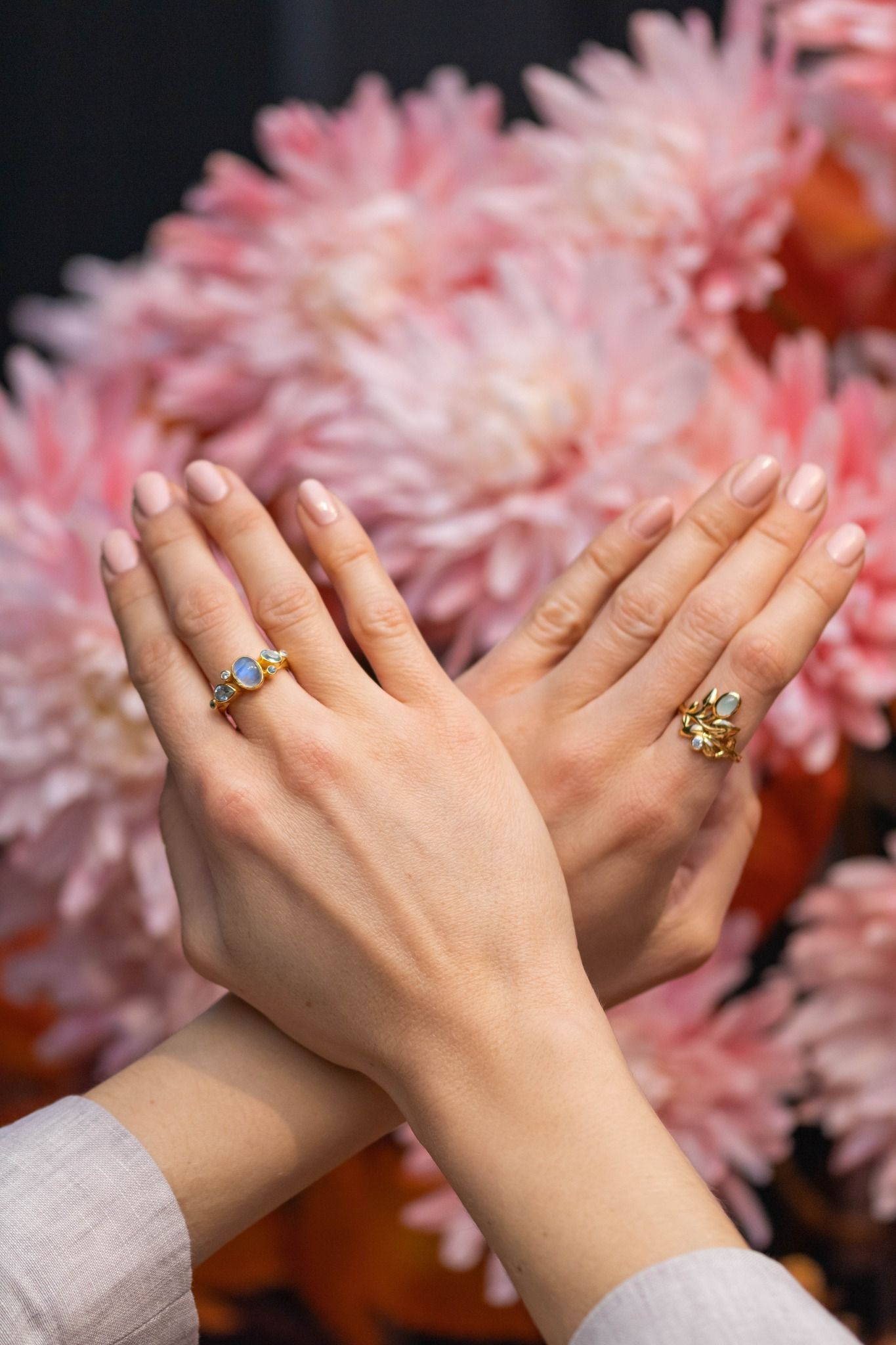 Twee handen met gekruiste ringen voor lichtroze bloemen.