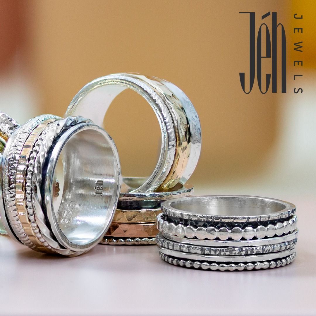 Drie draaiende zilveren ringen met gouden en gestructureerde details, met het merk