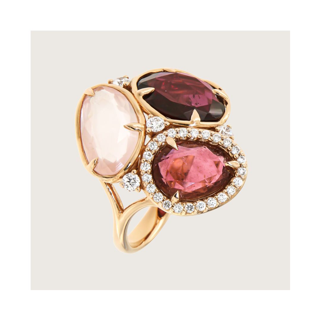 Gouden ring met een ovale roze edelsteen, een bordeauxrode edelsteen en een roze edelsteen omringd door diamanten.