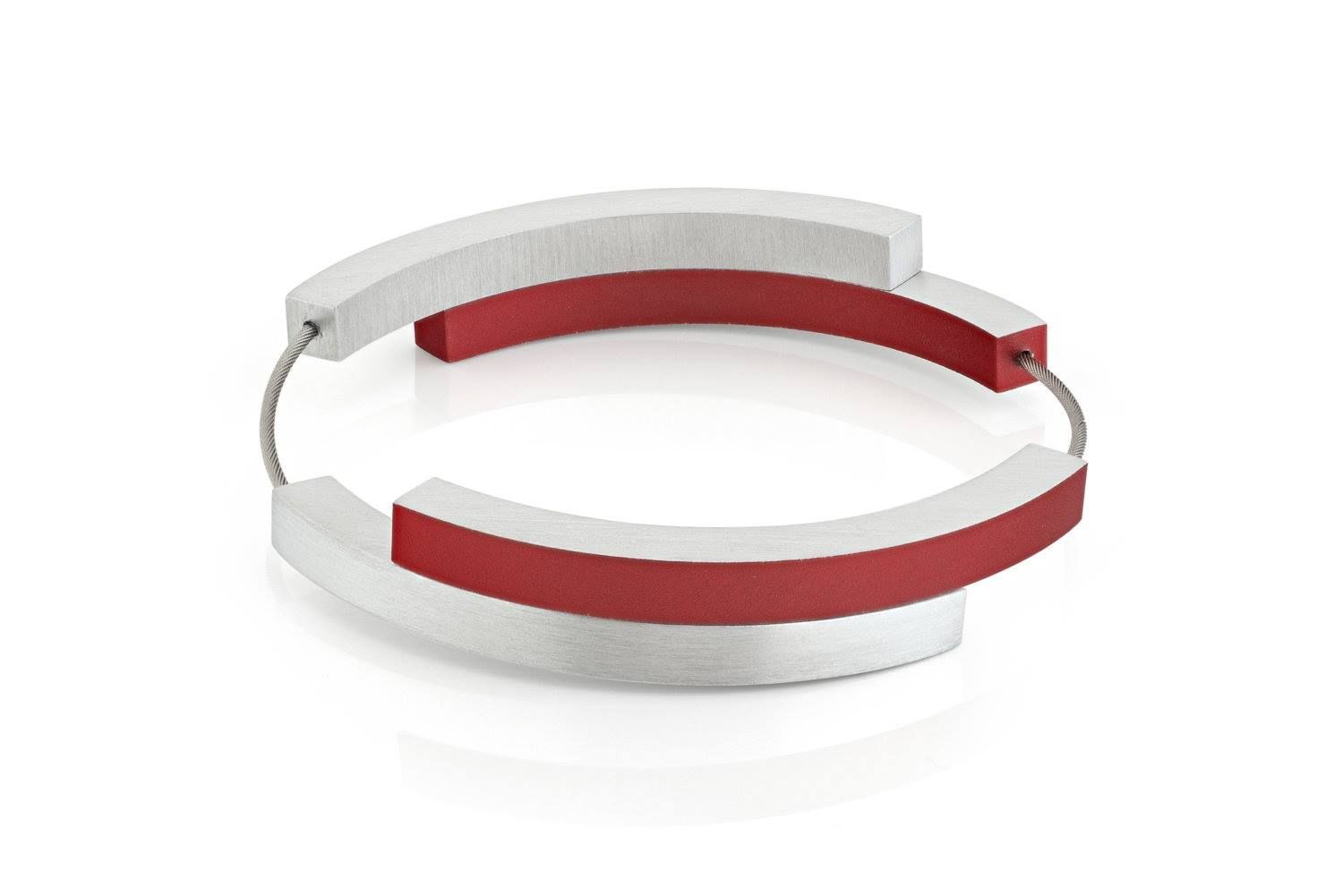 Zilveren en rode gebogen armband op een witte achtergrond.