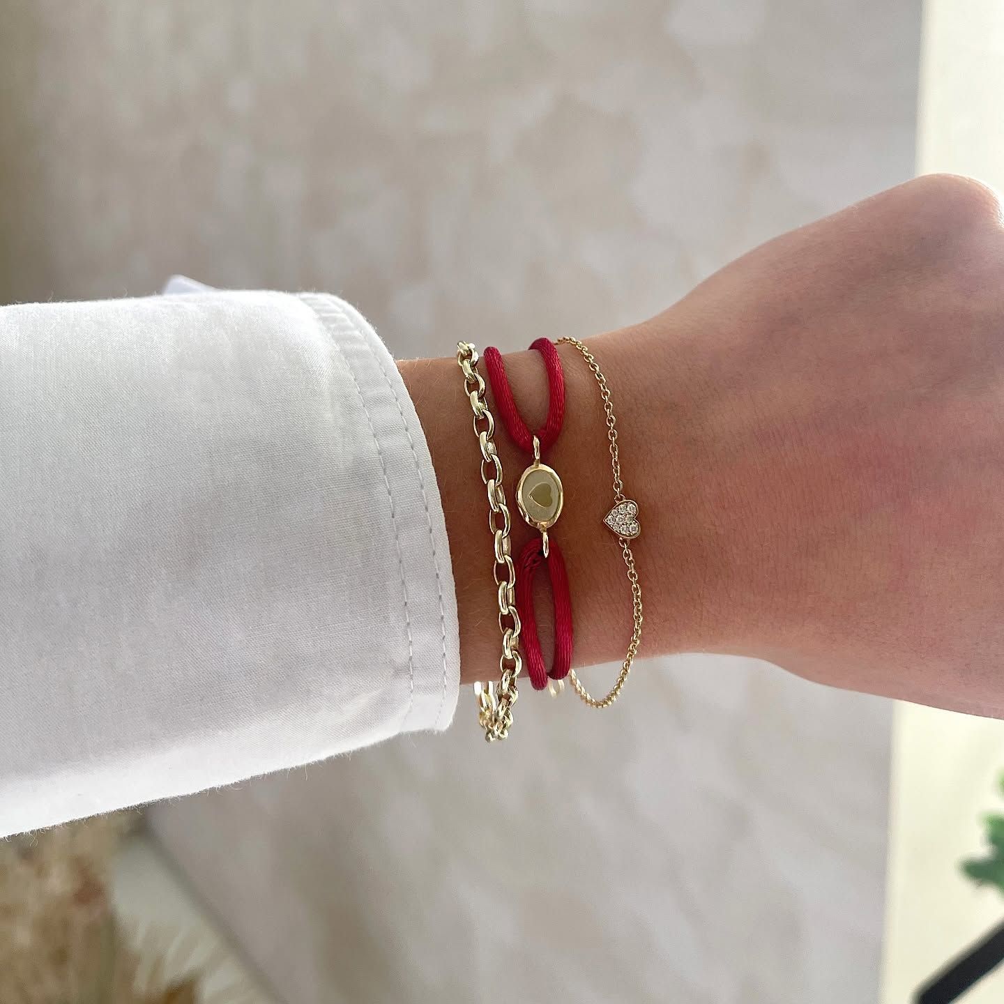 Pols met een stapel kleurrijke armbanden: groene, roze, blauwe en gouden accenten.